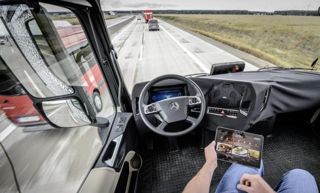 无人驾驶卡车驾驶员正在浏览电脑,让卡车自动行驶